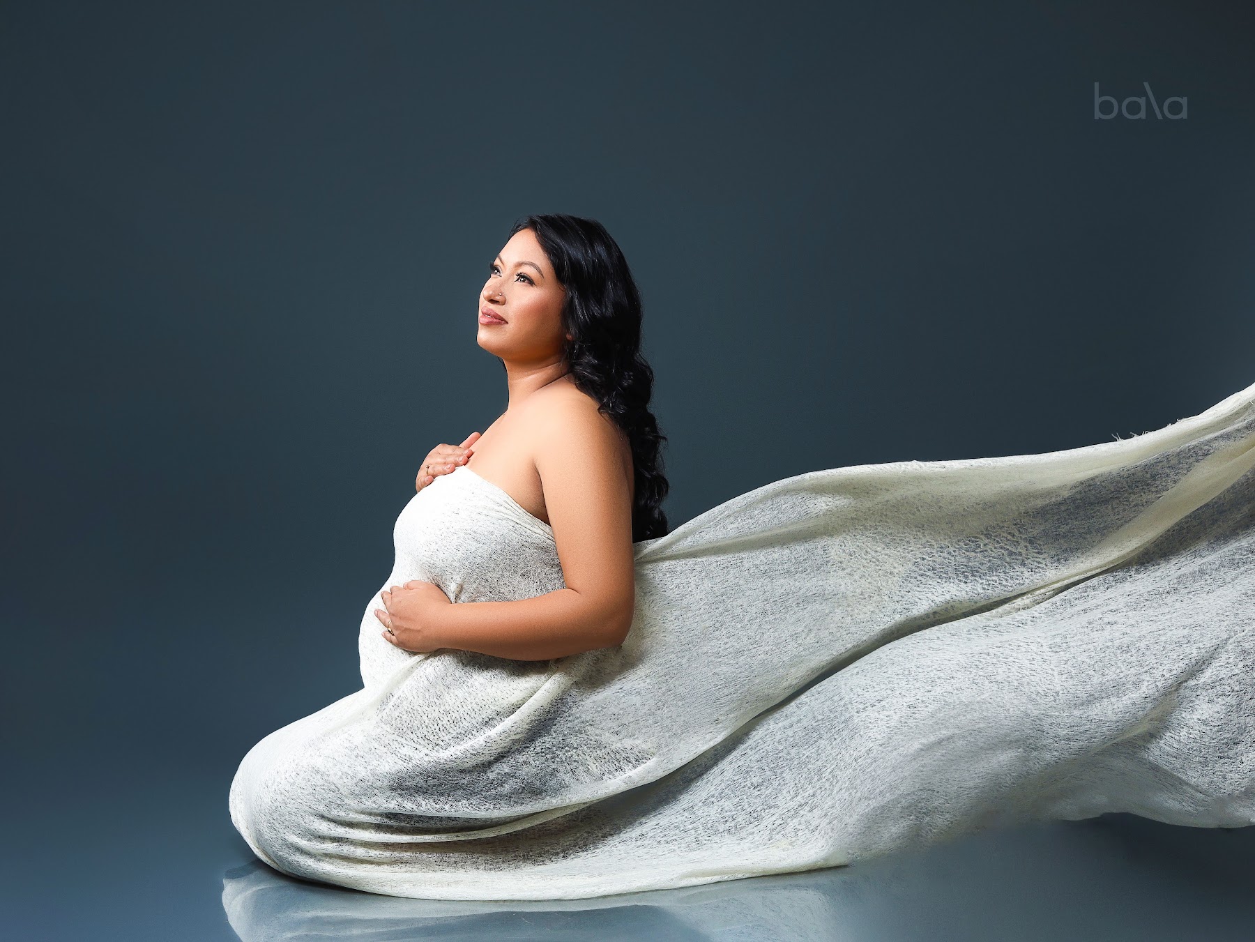 Woman draped in a flowing ivory cashmere wrap against a dark studio backdrop