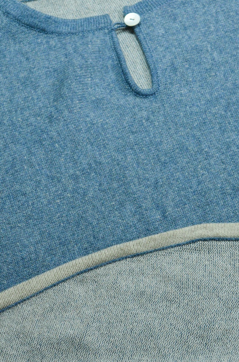 Detail of a blue knitted cashmere sweater with a contrast-tipped hem