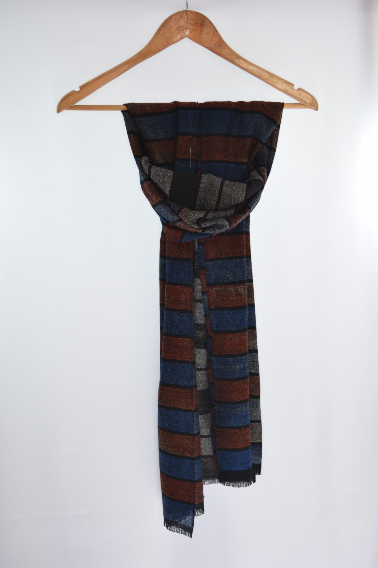 Navy and rust striped woven cashmere scarf on a wooden hanger