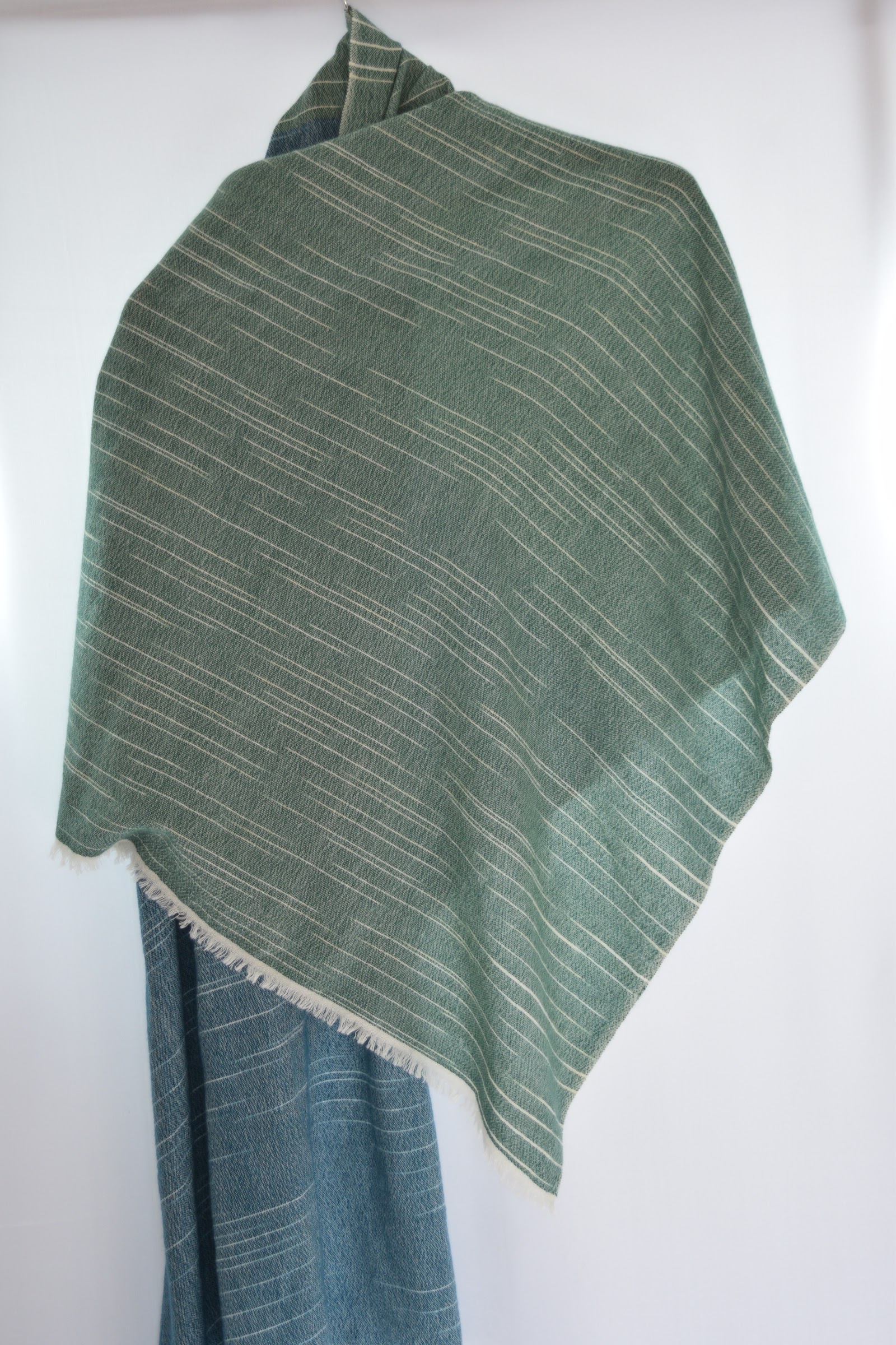 Olive green pinstripe woven cashmere stole draped on a mannequin